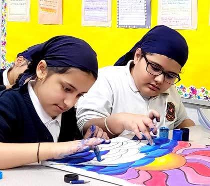 Two students finger-painting a colourful design during a club activity